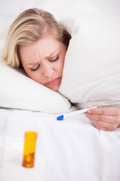istock Sick woman looking at her thermometer 846168022