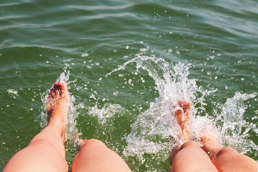 Two pairs of feet splash in the water.