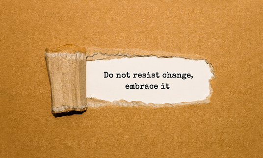 The text Do not resist change embrace it appearing behind torn brown paper