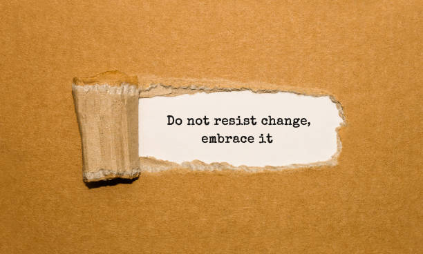 The text Do not resist change embrace it appearing behind torn brown paper stock photo