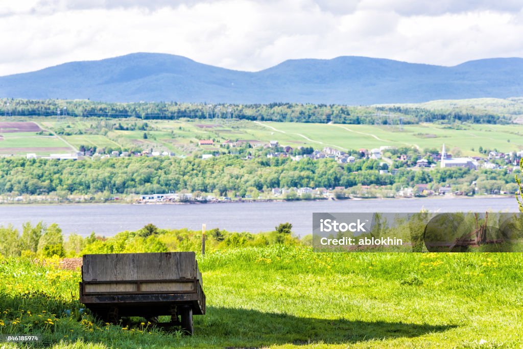 Old vintage wooden wagon overlooking Saint Lawrence river in summer landscape field in countryside with small village houses Abandoned Stock Photo