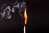 Matches stick with the flame and smoke burning, isolated on a black background
