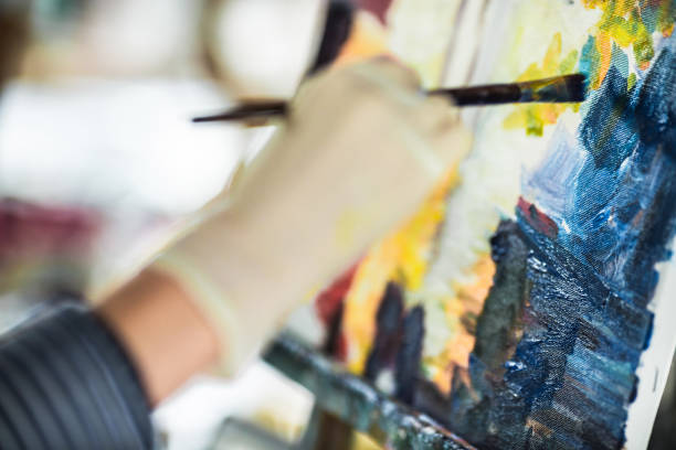 istock artist's hand with brush painting on canvas 846221614
