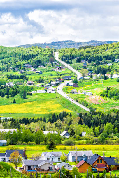 istock Les Eboulements, Charlevoix, Quebec, Canada cityscape or skyline with main highway steep curvy road going vertically up, patch farm green dandelion field, scattered village houses 846225126