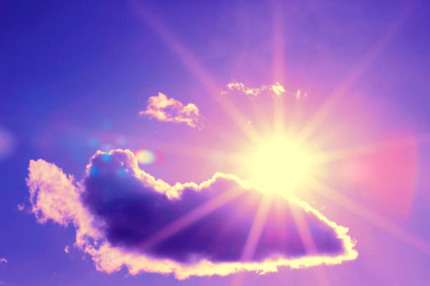 Bright sun with beautiful beams in the sky with clouds. Toned in purple color, space for copy.