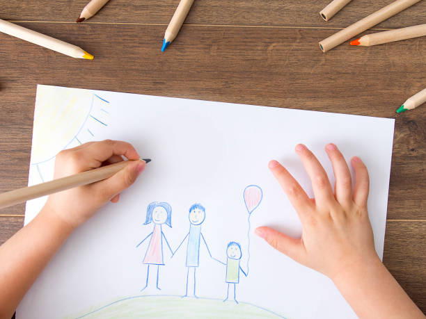 Kid drawing a happy family Kid drawing on white paper her happy family. Top view crayon photos stock pictures, royalty-free photos & images