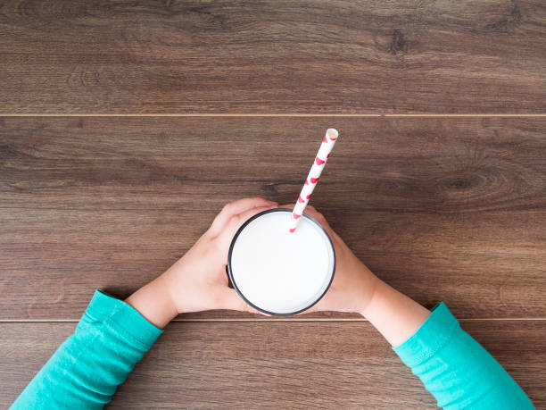 Child holding a glass of milk on dark rustic table