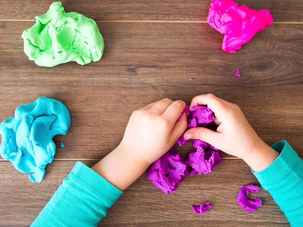 kid playing with a modeling compound on a dark background - clay imagens e fotografias de stock