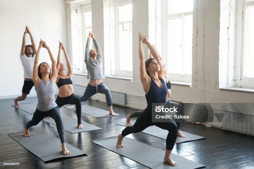 Groupe de jeunes sportifs en guerrier une pose, studio - Photo de Yoga libre de droits