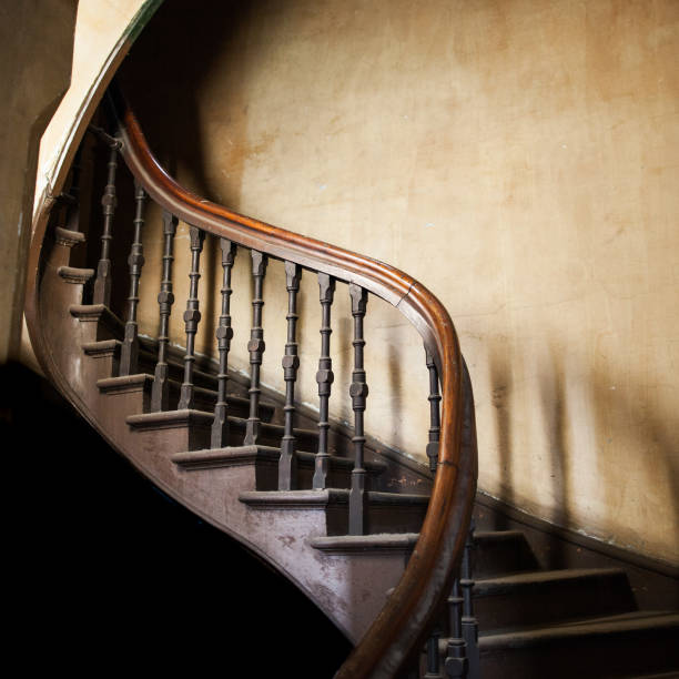 istock Vintage wooden winding staircase going up with copy space on old decaying wall 846243010
