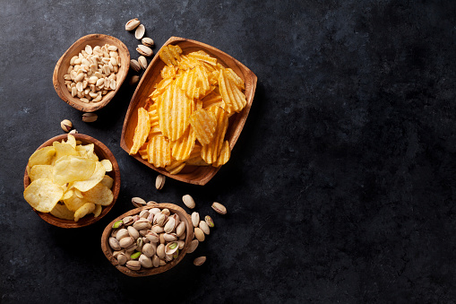 Beer snacks on stone table. Various nuts, potato chips. Top view with copy space