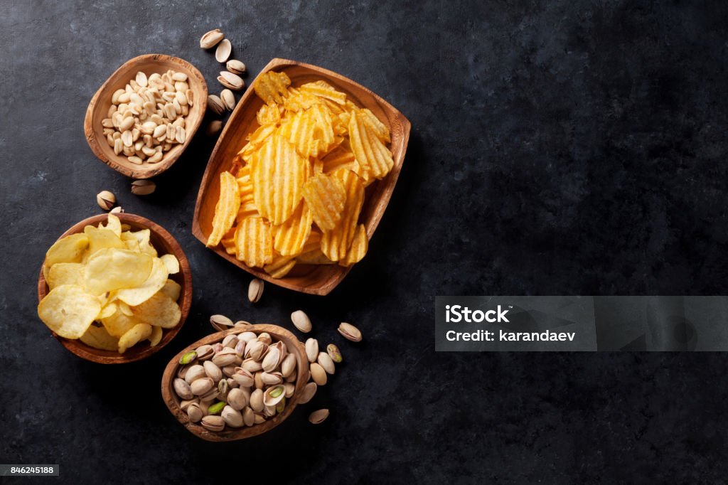 Beer snacks Beer snacks on stone table. Various nuts, potato chips. Top view with copy space Snack Stock Photo