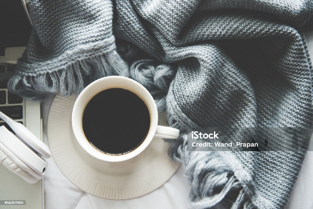 The laptop working and listen music on the white bed and coffee with marshmallow, warm knitted sweater in the sunny day.  Cozy winter home morning holiday.  Music and Lifestyle Concept. Bed - Furniture Stock Photo