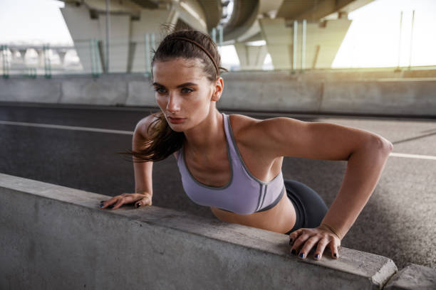 istock Young woman doing pushups in the street, looking away 846263270