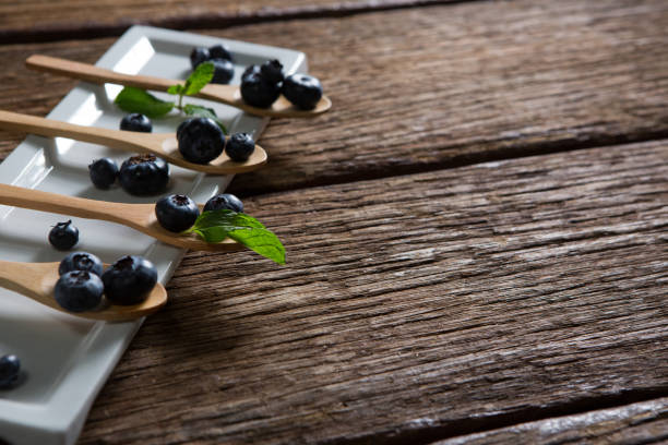 Close-up of blueberries with mint in wooden spoon arranged on tray