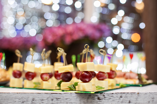 Appetizer of grape, pineapple cubes and cheese are on wooden skewers