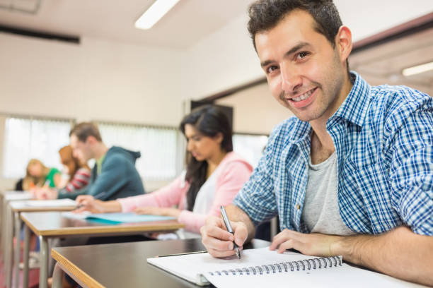istock Smiling male student with others writing notes in classroom 846275792