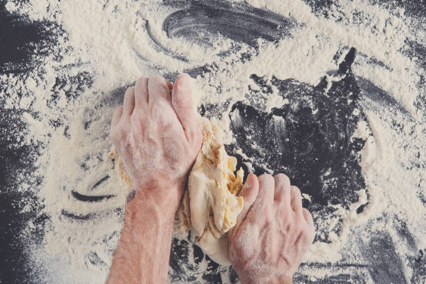 istock Hands top view knead dough on black background 846306798