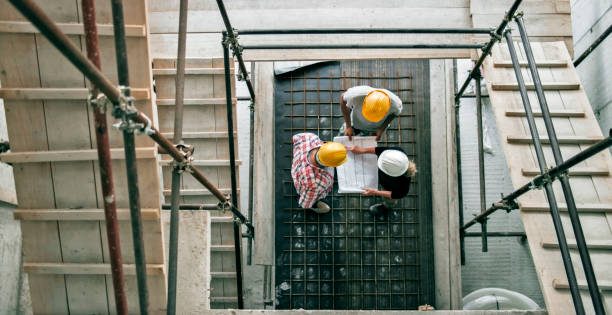 istock Female architect explaining details of plan to site manager and foreman standing at bottom of scaffold staircase 846306932