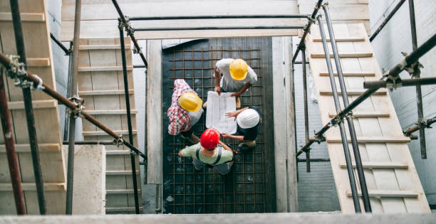 istock Female architect explaining details of plan to site manager and foreman standing at bottom of scaffold staircase 846306946