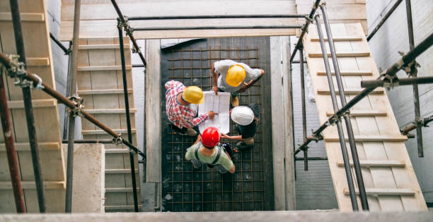 istock Female architect explaining details of plan to site manager and foreman standing at bottom of scaffold staircase 846307064