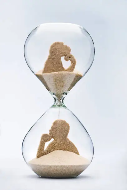 Theory of evolution concept, with falling sand taking the shape of a monkey and a man inside a hourglass