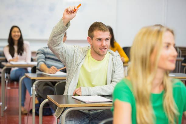 istock Male student raising hand by others in classroom 846329704
