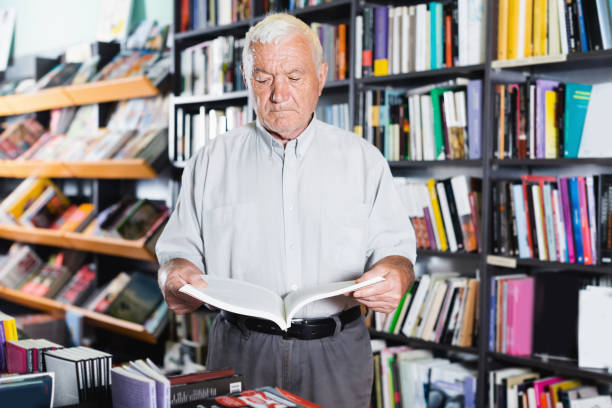 istock Mature male is looking book for reading in bookstore 846330212