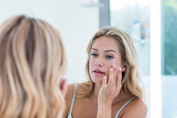 istock Smiling pretty woman applying cream on her face 846330408