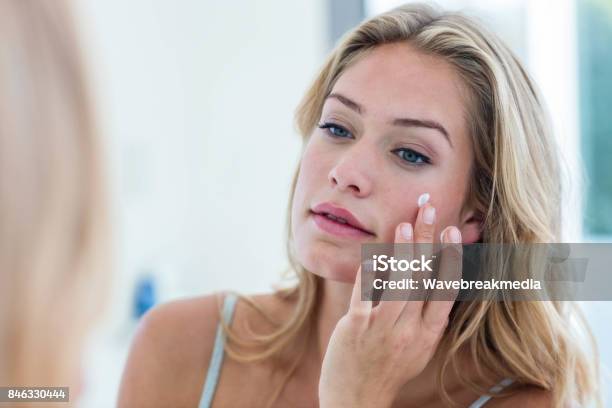 Smiling Pretty Woman Applying Cream On Her Face Stock Photo - Download Image Now - Suntan Lotion, Human Face, Women