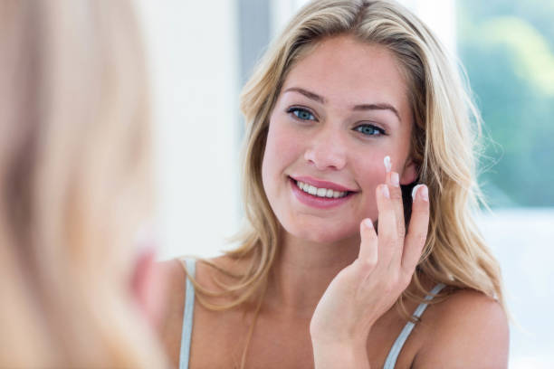 istock Smiling pretty woman applying cream on her face 846330506
