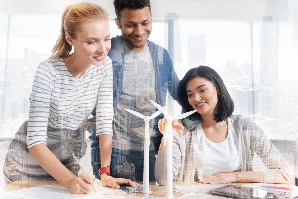 istock Smiling coworkers looking at small windmill 846333604