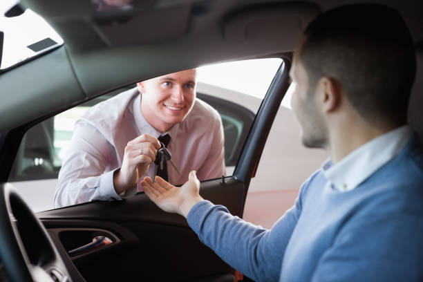 istock Smiling salesman giving keys to a customer 846333816
