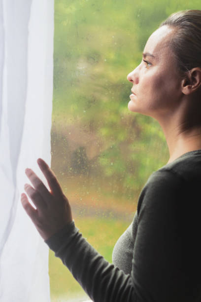 istock Woman standing by the window alone 846337632
