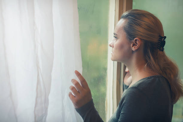 istock Woman standing by the window alone 846337634