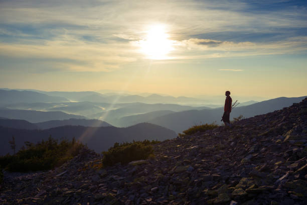 At the edge of the world. Silhouette of hiker on top of a mountain in fog and clouds in the mountains