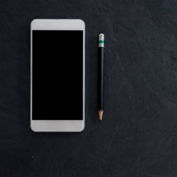 istock cell phone and black pencil on black stone background. flat lay style 846343620
