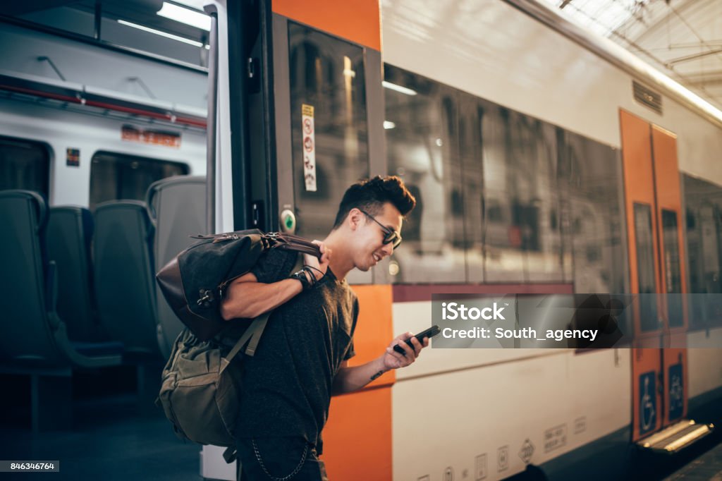 Finally home Handsome young chinese hipster waiting for a train at the train station. Travel Stock Photo