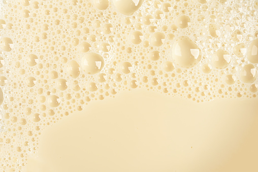 Soy milk bubble foam background on top view close up