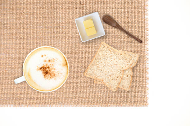 Cappuccino coffee with bread and butter on burlap sackcloth,white background. Simple breakfast cappuccino coffee with bread and butter.