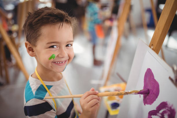 Portrait of happy schoolboy panting on canvas Portrait of happy schoolboy panting on canvas during drawing class panting photos stock pictures, royalty-free photos & images