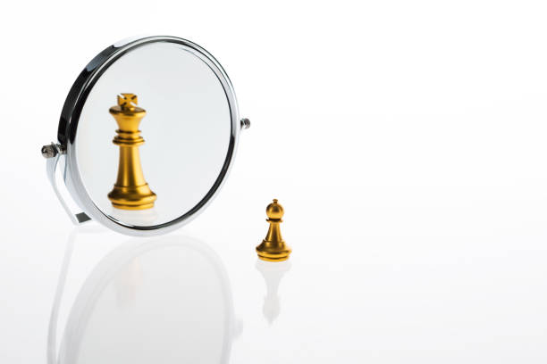 Golden chess pawn imagining itself as a king Golden chess pawn imagining itself as a king mirror object stock pictures, royalty-free photos & images