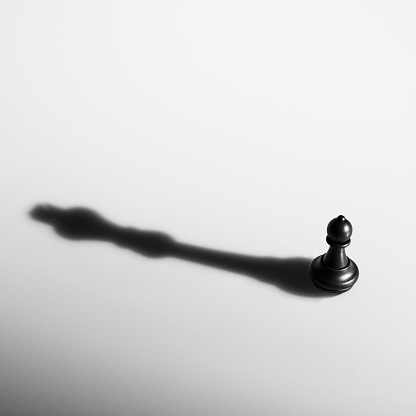 Black chess pawn with the shadow of a king