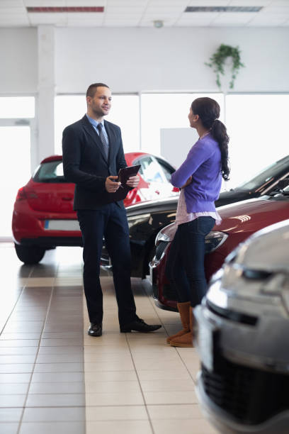 istock Salesman and a woman talking next to a car 846377772