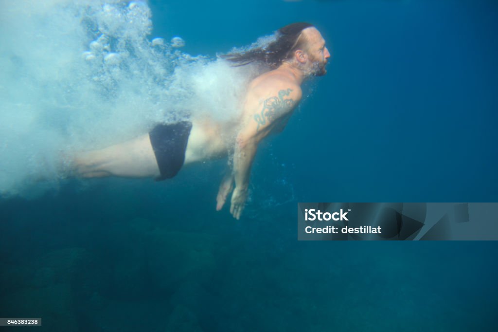 Man swimming underwater Man swimming underwater in blue transparent sea water Active Lifestyle Stock Photo
