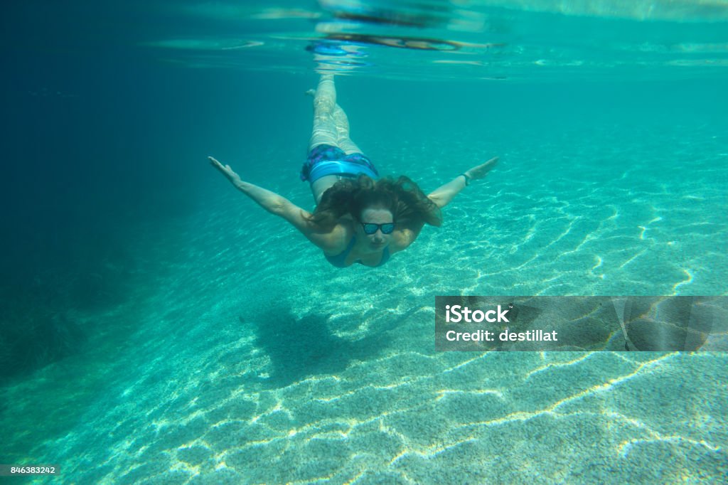 Woman swimming underwater Woman swimming underwater in blue transparent sea water Active Lifestyle Stock Photo