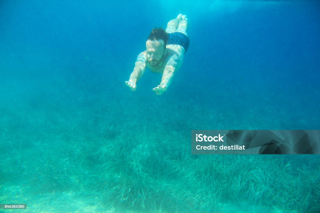 Man swimming underwater Man swimming underwater in blue transparent sea water Active Lifestyle Stock Photo