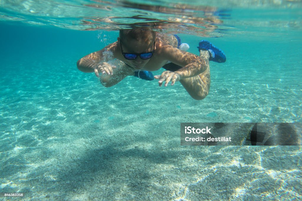 Child swimming underwater Child swimming underwater in blue transparent sea water Active Lifestyle Stock Photo