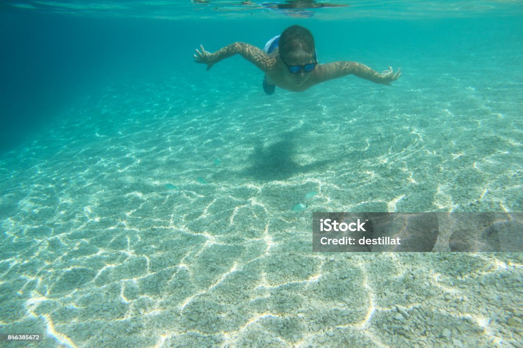 Child swimming underwater Child swimming underwater in blue transparent sea water Active Lifestyle Stock Photo