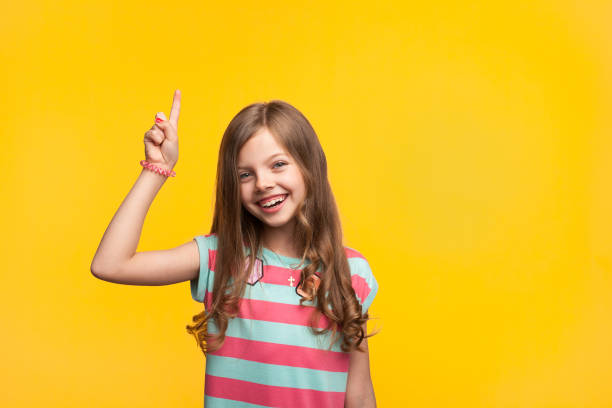istock Cheerful little girl pointing up on orange 846398228